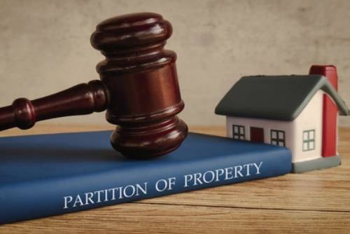 Gavel and a miniature house on a book titled PARTITION OF PROPERTY, representing legal property division.