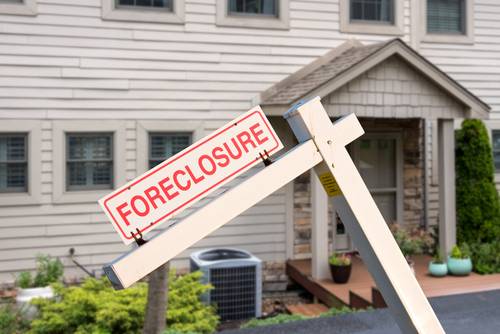 foreclosure sign in front of a modern townhome or townhouse to illustrate recession fears due to coronavirus