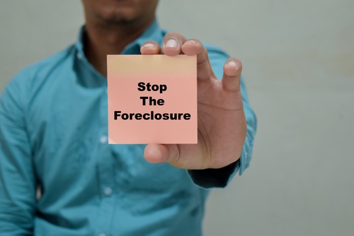 Businessman holds in hands a card with the name of the stop the foreclosure.